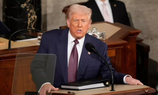 Donald Trump speaking at a White House event with U.S. flags in the background, suggesting a trade deal announcement.